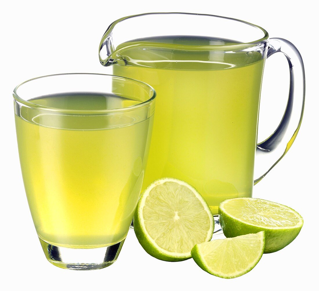 Lime juice in jug and glass and fresh limes