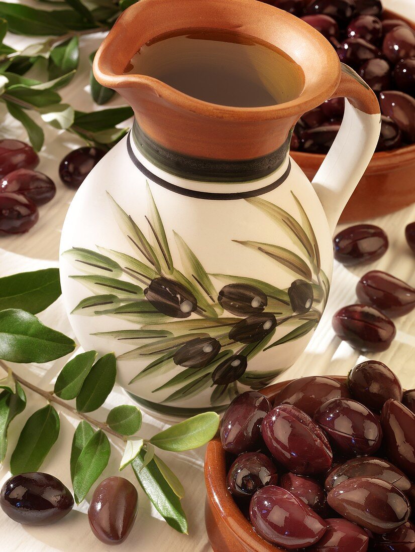 A jug of olive oil, olives and olive branches