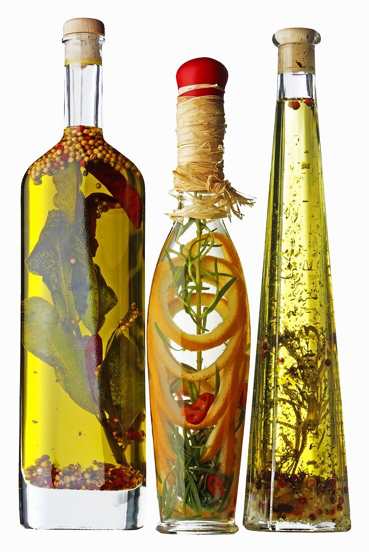 Drei Flaschen Pflanzenöl mit Kräutern, Gewürzen aromatisiert