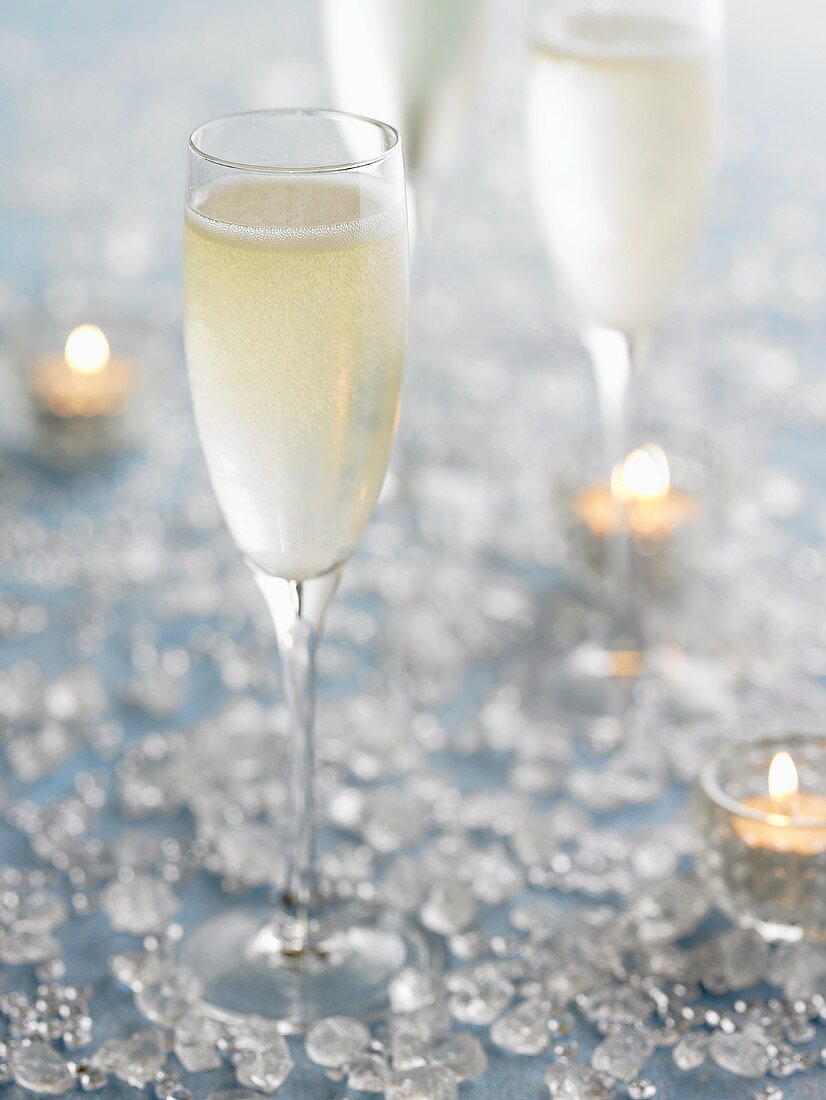 Mehrere Gläser Champagner, Kerzen und Kristalle