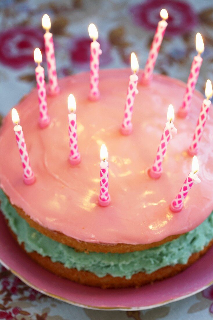 Geburtstagstorte mit rosafarbener Zuckerglasur und Kerzen