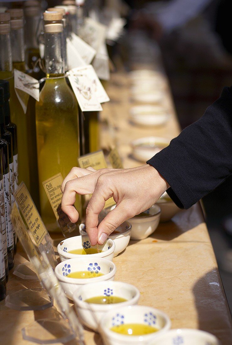 Jemand testet Olivenöl an einem Marktstand