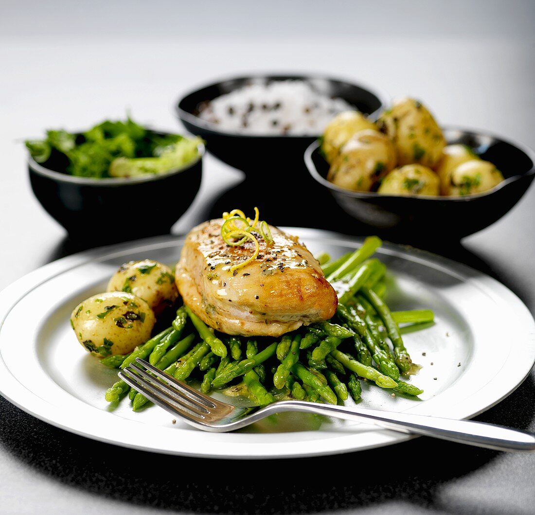Chicken breast on green asparagus with parsley potatoes
