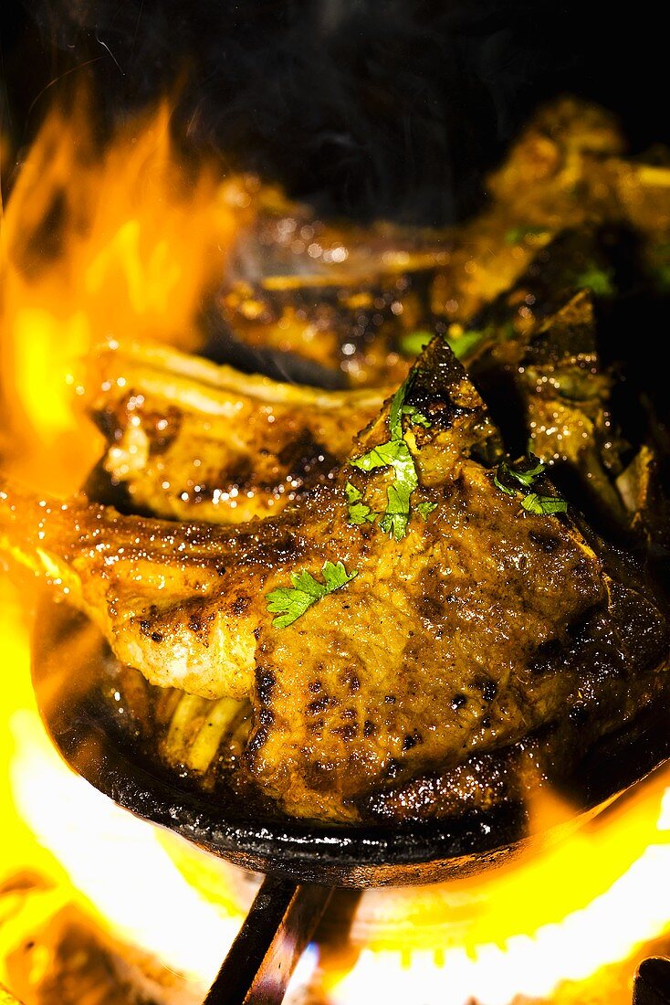 Marinated lamb chops in cast-iron frying pan over a flame