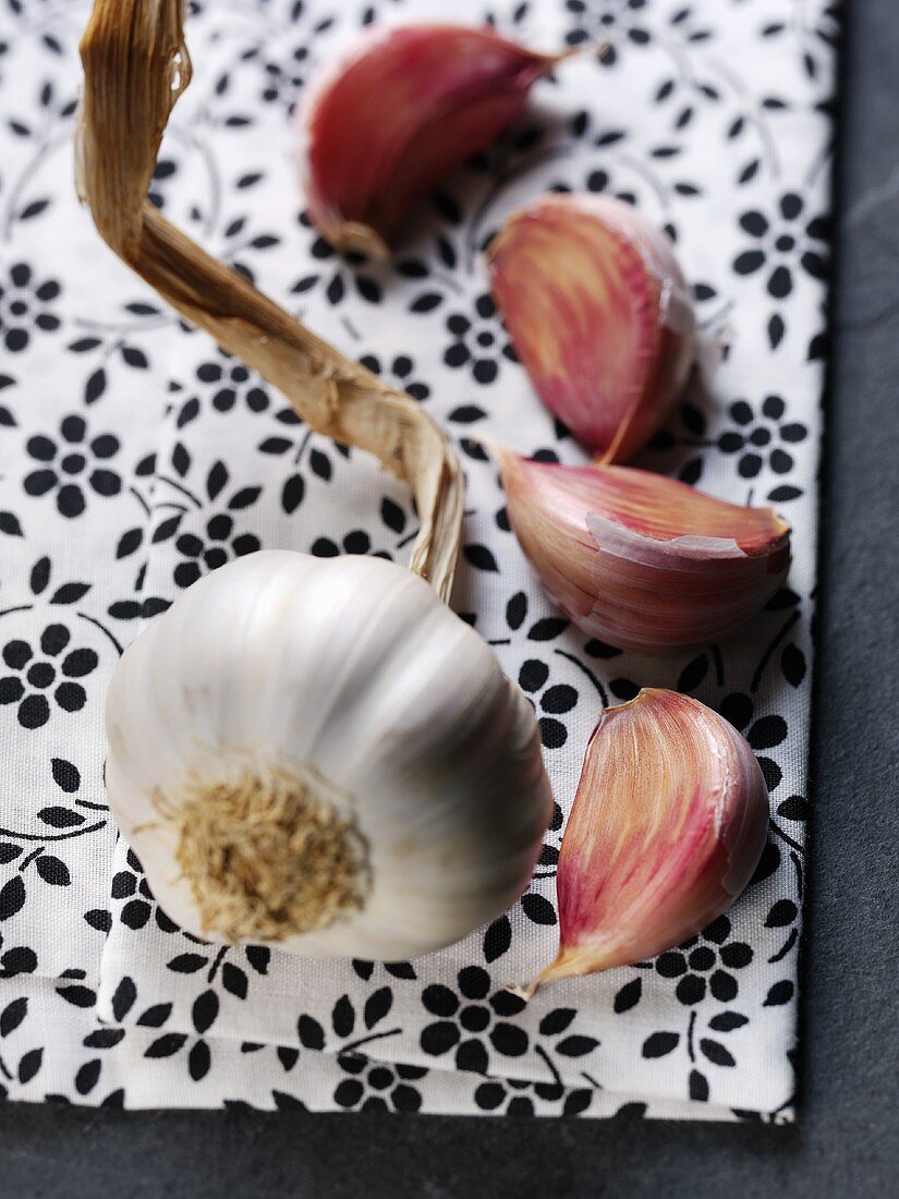 Garlic bulb and cloves on flowery background