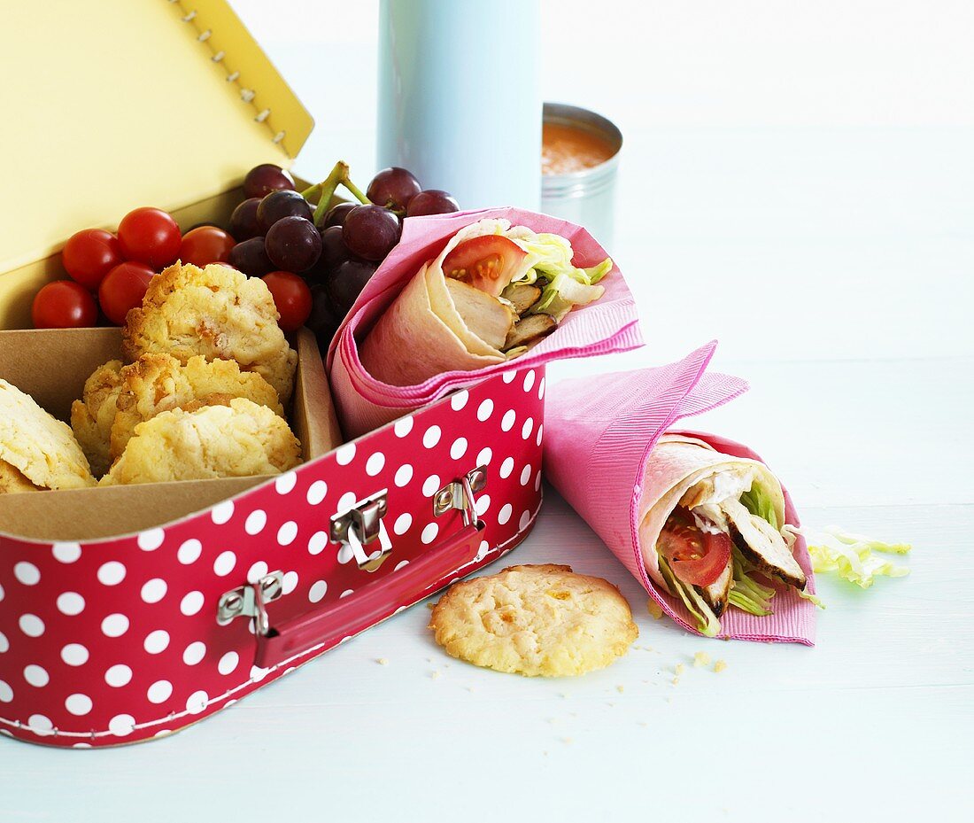Lunch box with wraps, cookies, grapes and cherry tomatoes