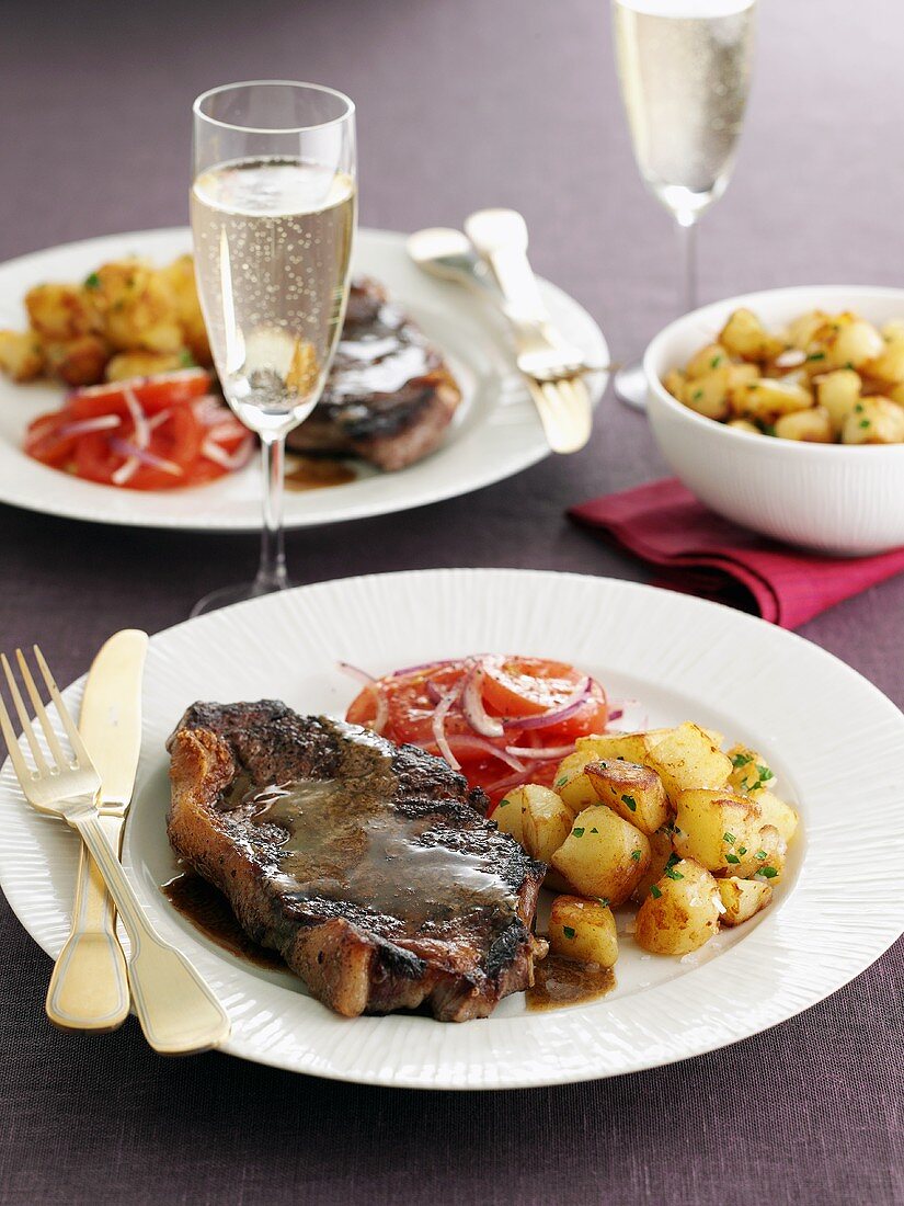 Beefsteak with butter sauce, fried potatoes and tomato salad