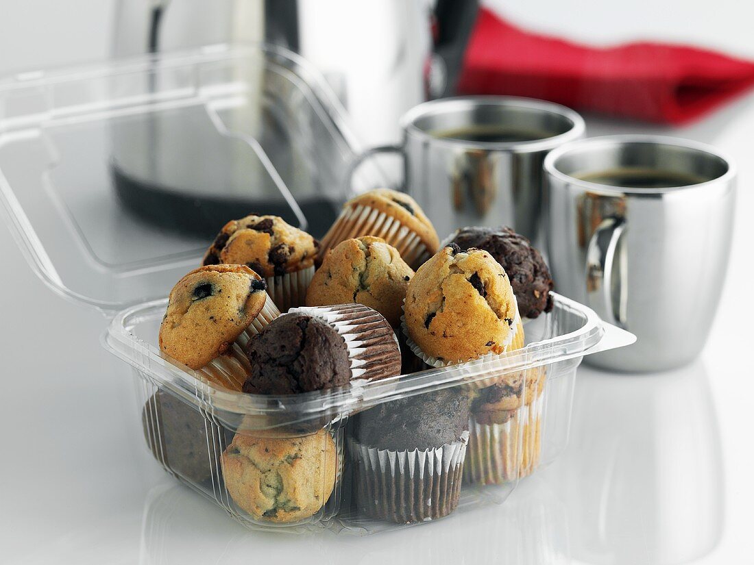 Assorted mini-muffins in plastic container to take away, coffee