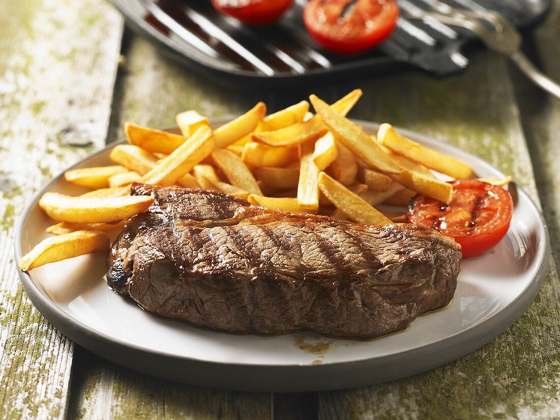 Gegrilltes Steak mit Pommes frites und Grilltomate