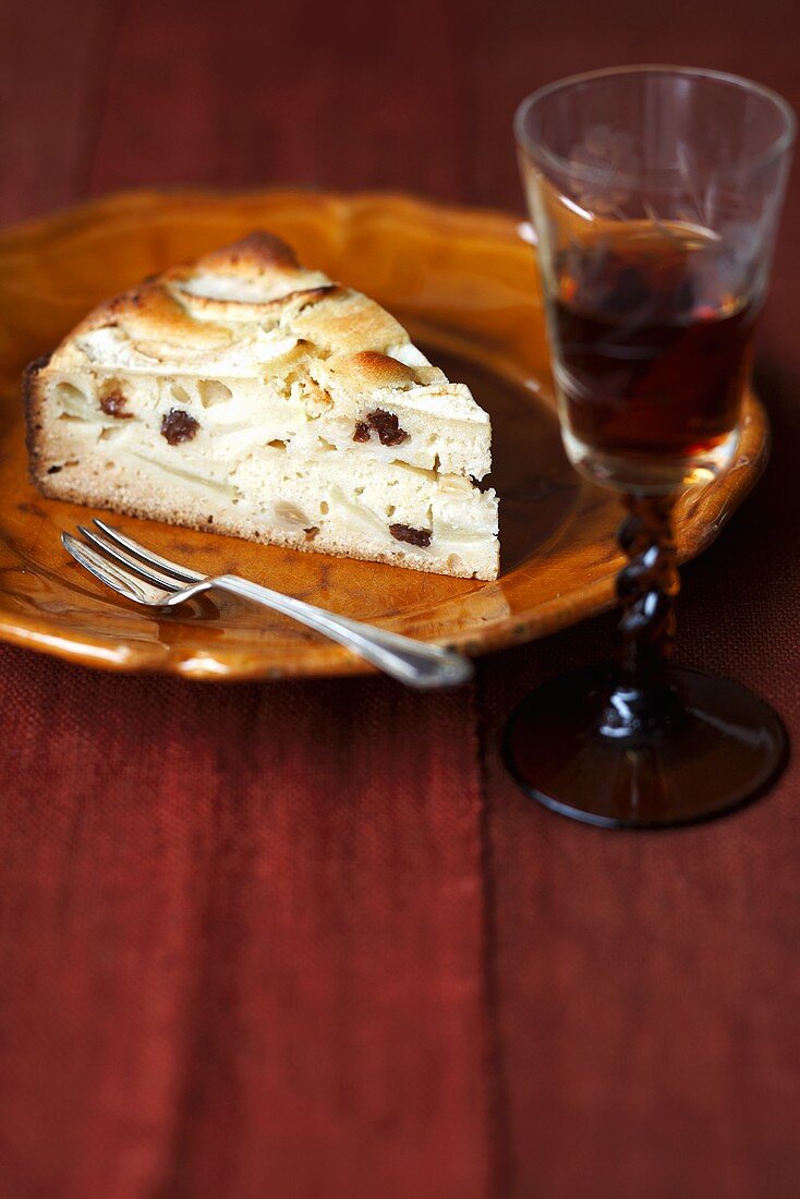 A slice of apple cake with a glass of liqueur