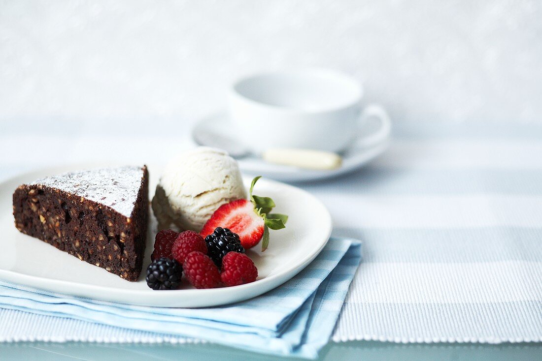 Ein Stück Schoko-Haselnusskuchen mit Vanilleeis und Beeren