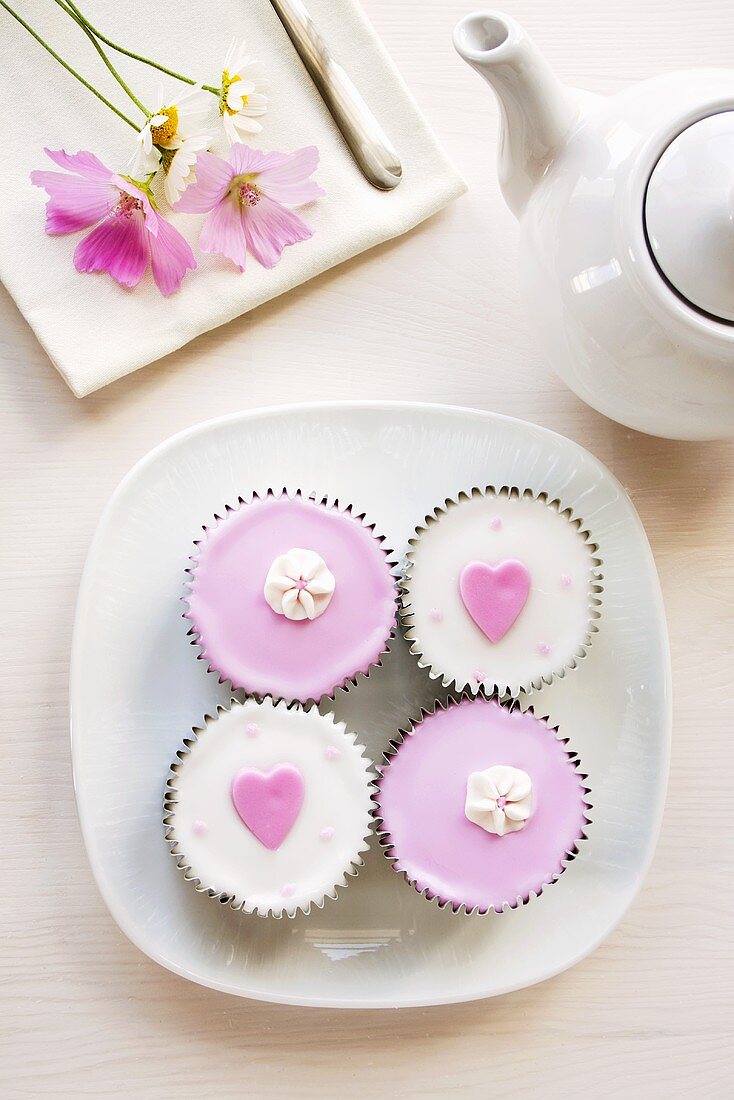 Cupcakes dekoriert mit Herzen und Zuckerblüten (Draufsicht)
