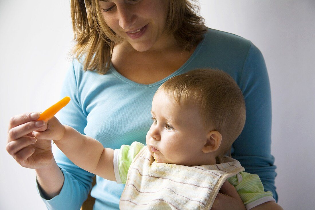 Mother giving baby a carrot