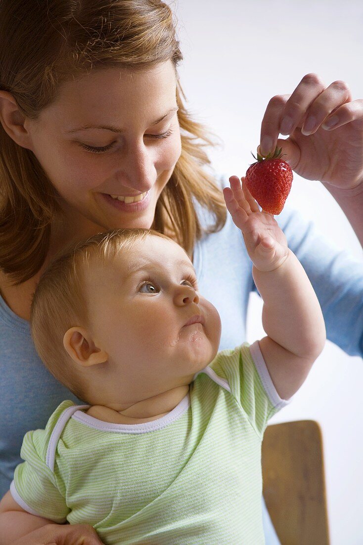 Mother giving baby a strawberry
