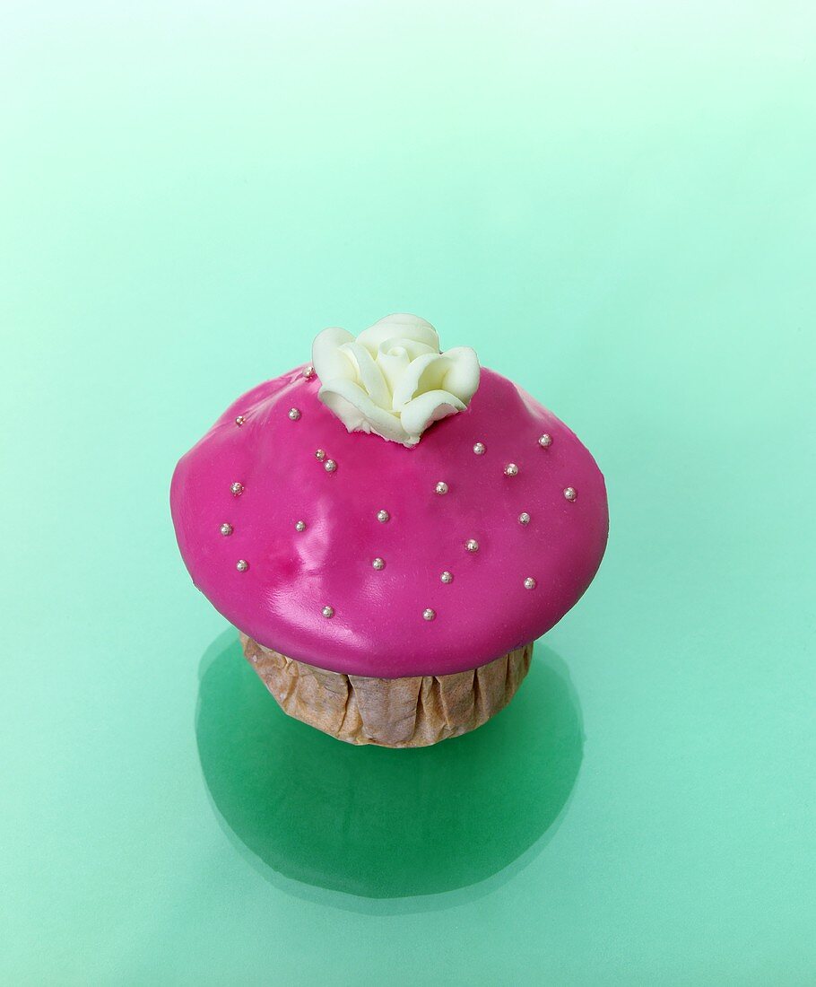 Muffin mit rosa Zuckerguss und Zuckerblüte