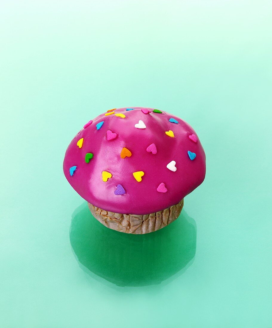 Muffin mit pinkfarbenem Zuckerguss und Zuckerherzen
