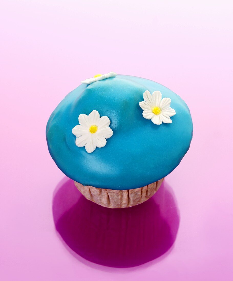 Muffin mit blauem Zuckerguss und Zuckerblüten
