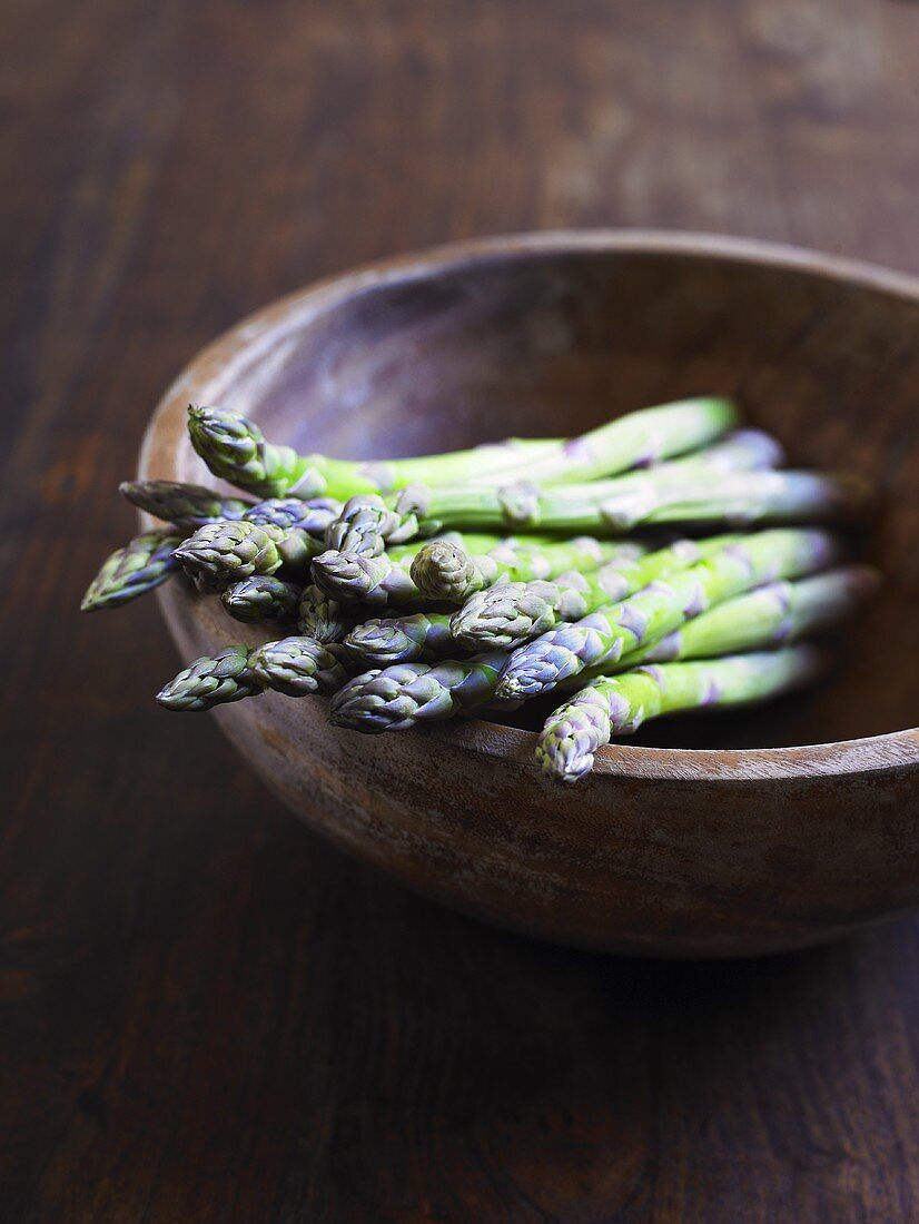 Green asparagus in wooden bowl