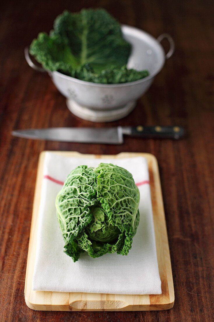 Fresh savoy cabbage on chopping board and in colander