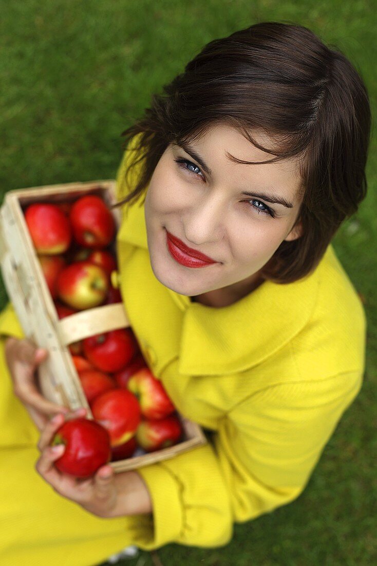 Frau hält Spankorb mit frischen roten Äpfeln
