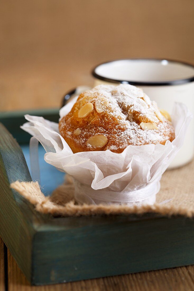Almond muffin and enamel mug on wooden tray