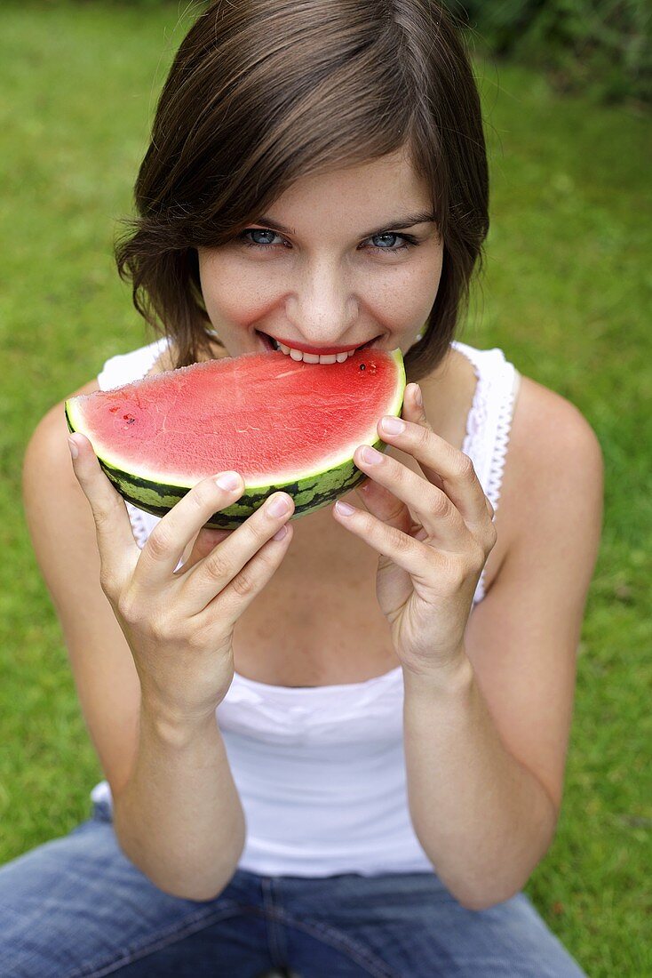 Junge Frau beisst in eine Wassermelone
