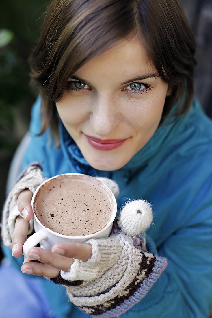 Junge Frau hält eine Tasse mit heißer Schokolade