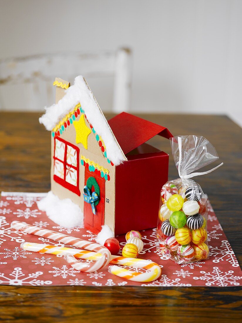 Christmas sweets and cardboard house on table mat