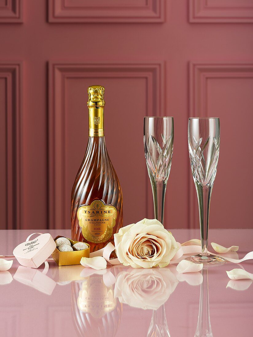 Champagnerflasche, Trüffelpralinen, Rosen und Sektgläser