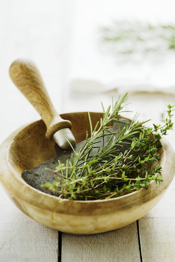 Rosemary and thyme in wooden bowl with mezzaluna