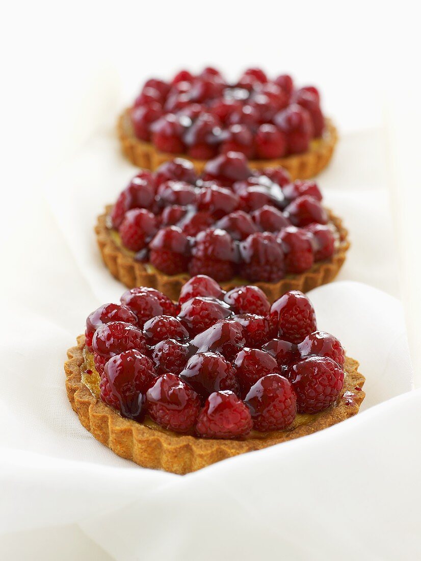 Three raspberry tarts with vanilla cream