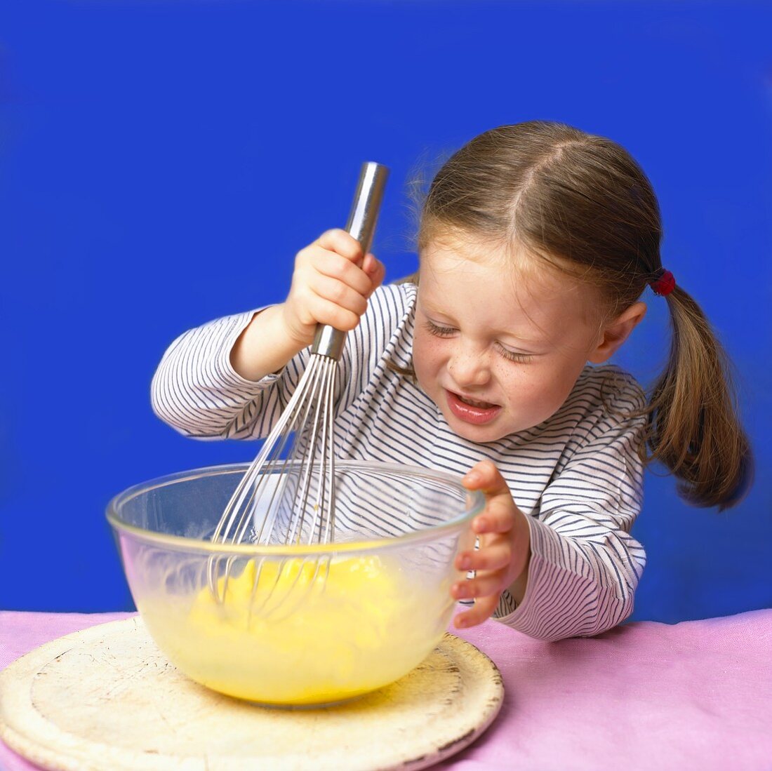 Little girl whisking egg yolks in bowl