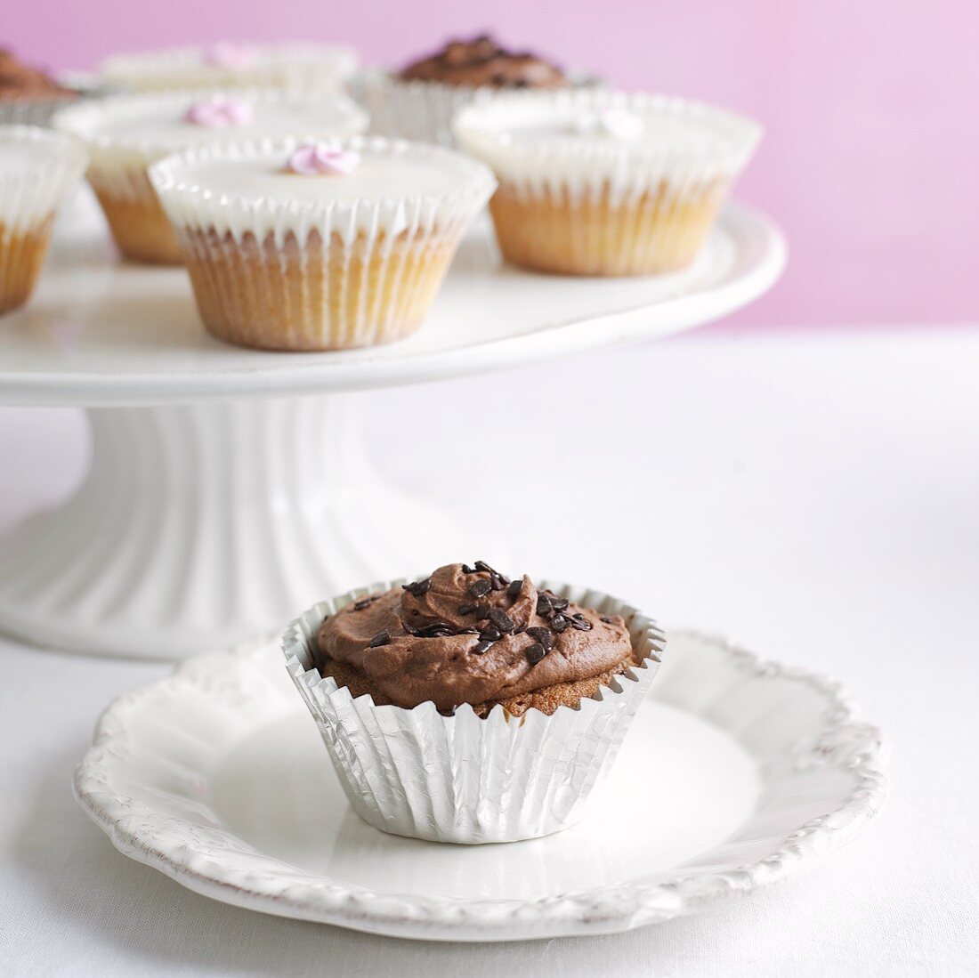 Verschiedene Cupcakes auf Kuchenständer und Teller