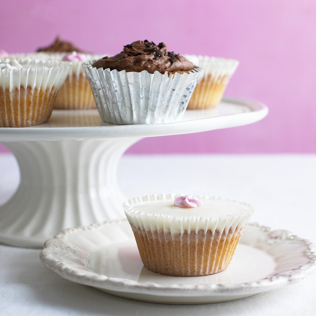 Verschiedene Cupcakes auf Kuchenständer und Teller