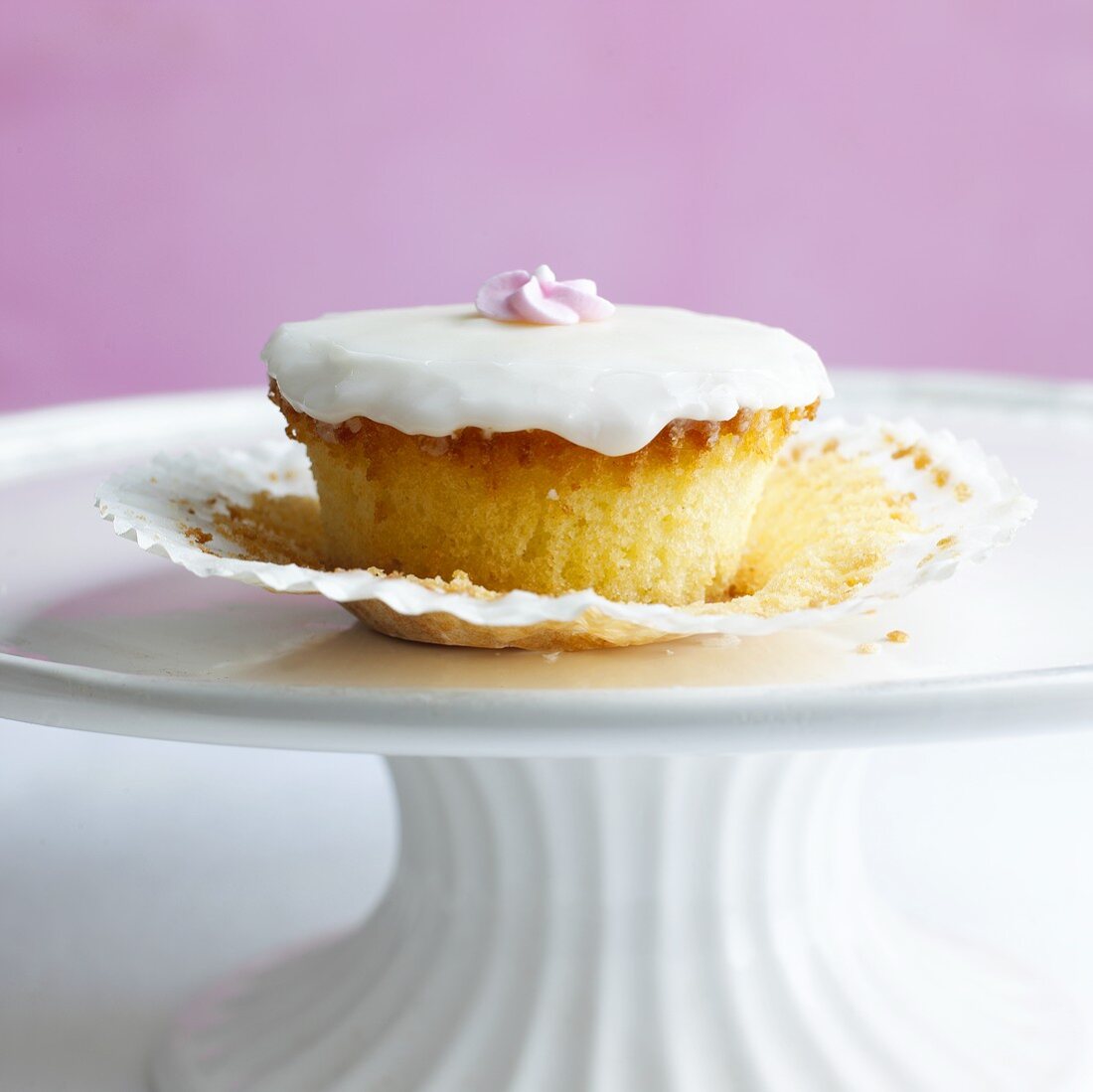 Cupcake mit Zuckerguss und Zuckerblume auf Kuchenständer