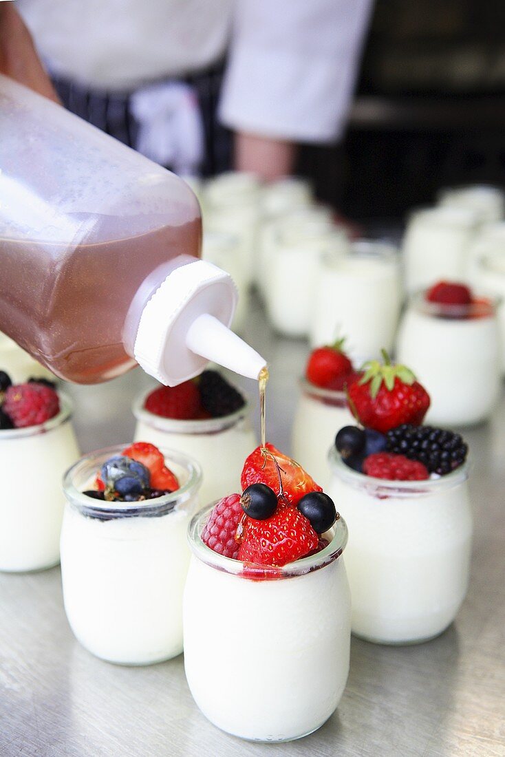 Joghurt mit Beeren mit Honig beträufeln