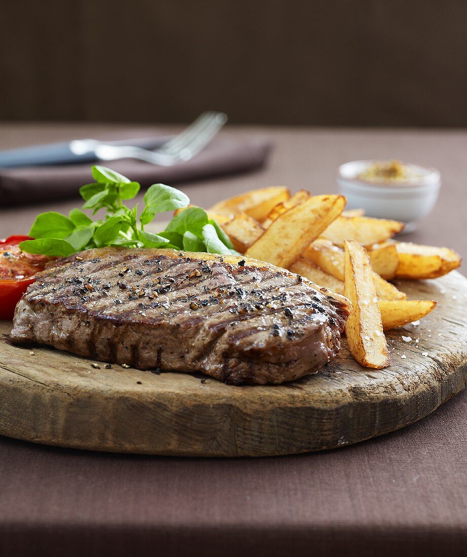 Beefsteak with chips on rustic wooden board