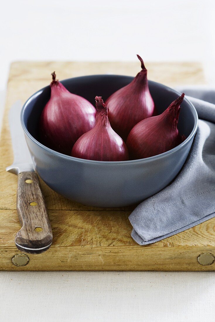 Red onions in bowl on chopping board