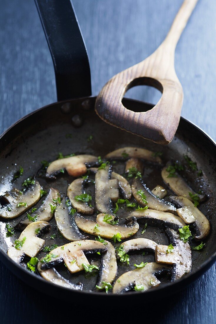 Gebratene Pilze mit Petersilie und Knoblauch in Pfanne