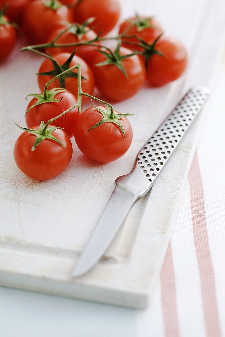 Cherry tomatoes on chopping board with knife