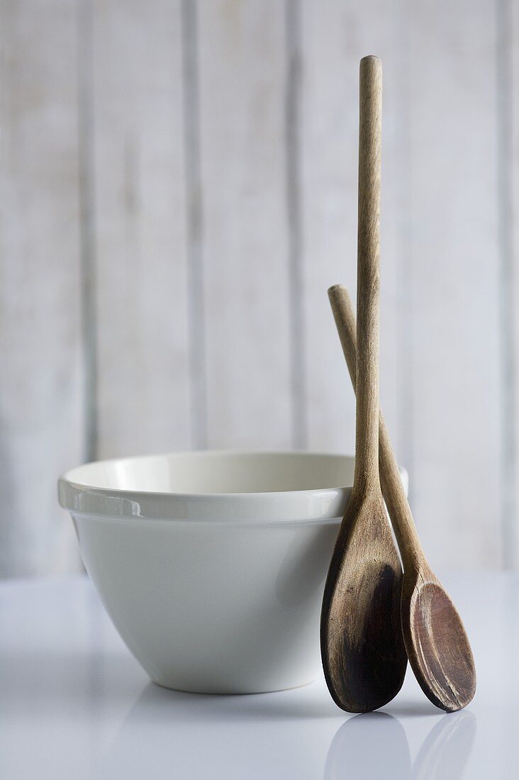 Old wooden spoons beside ceramic basin