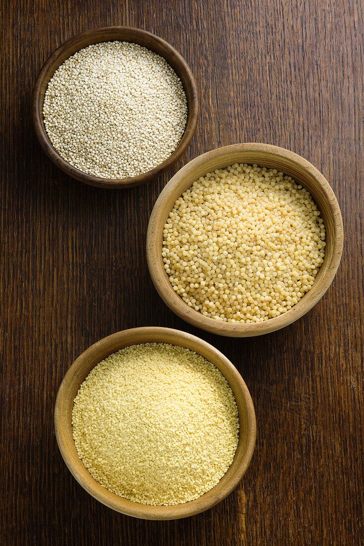 Quinoa und Couscous in Schalen auf Holzuntergrund