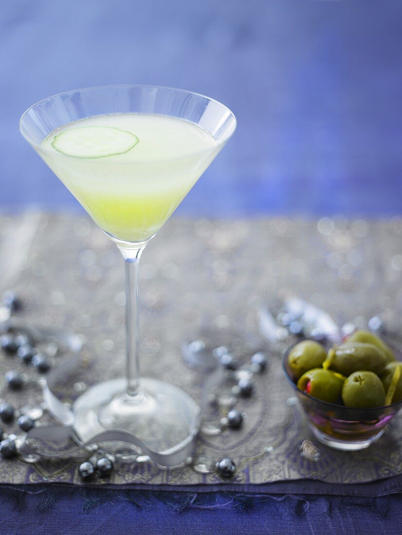 Martini with slice of cucumber, green olives