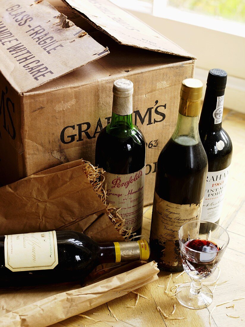 Various bottles of red wine in front of cardboard box