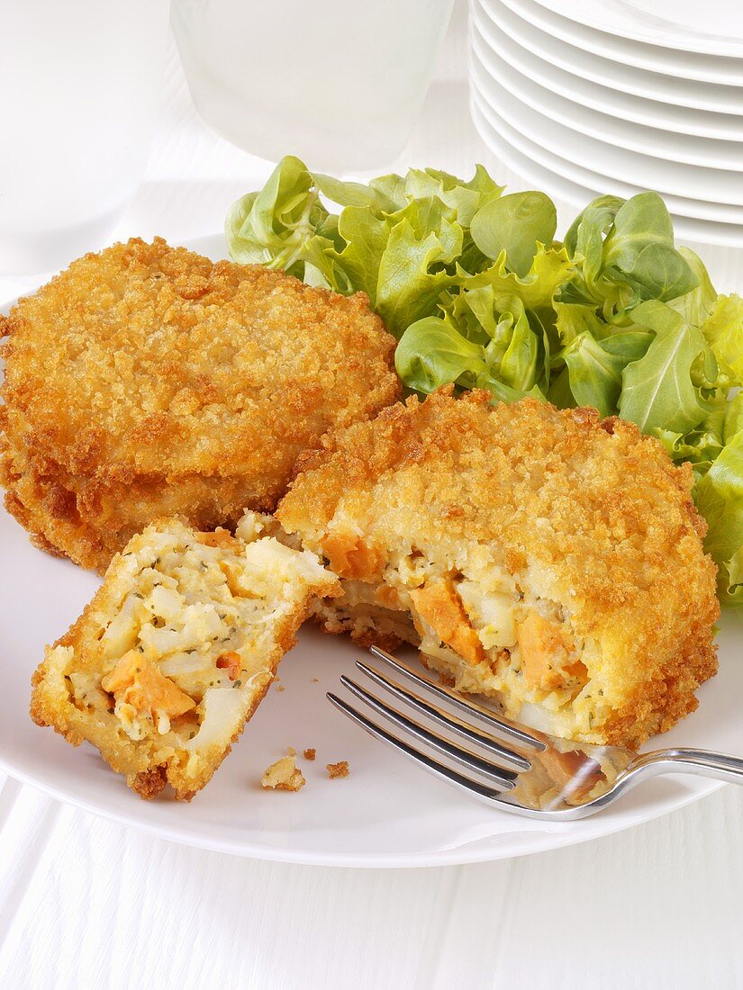 Vegetable cakes coated in breadcrumbs with a green salad