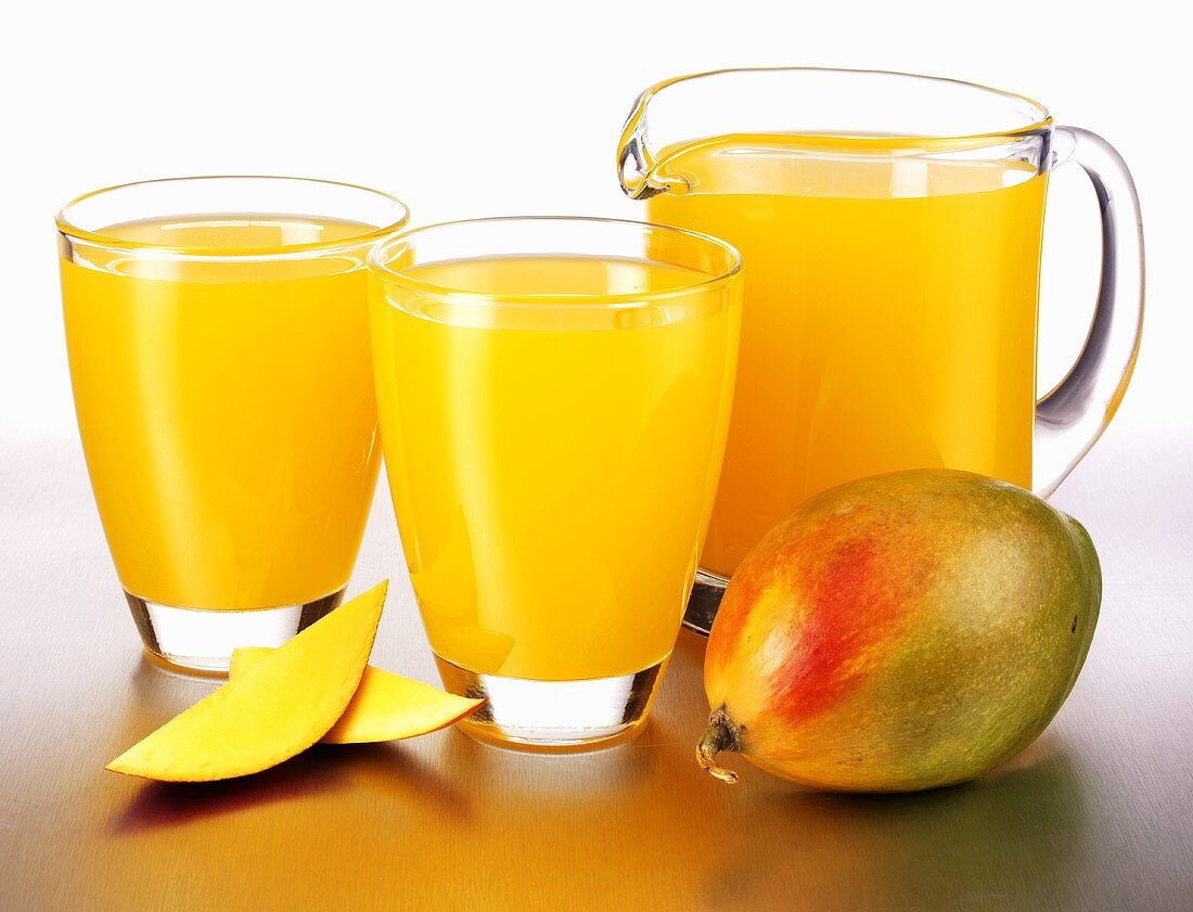Mango juice in glasses and a glass jug