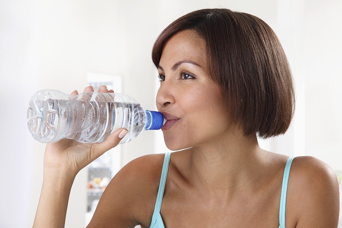 A woman drinking water out of a plastic bottle
