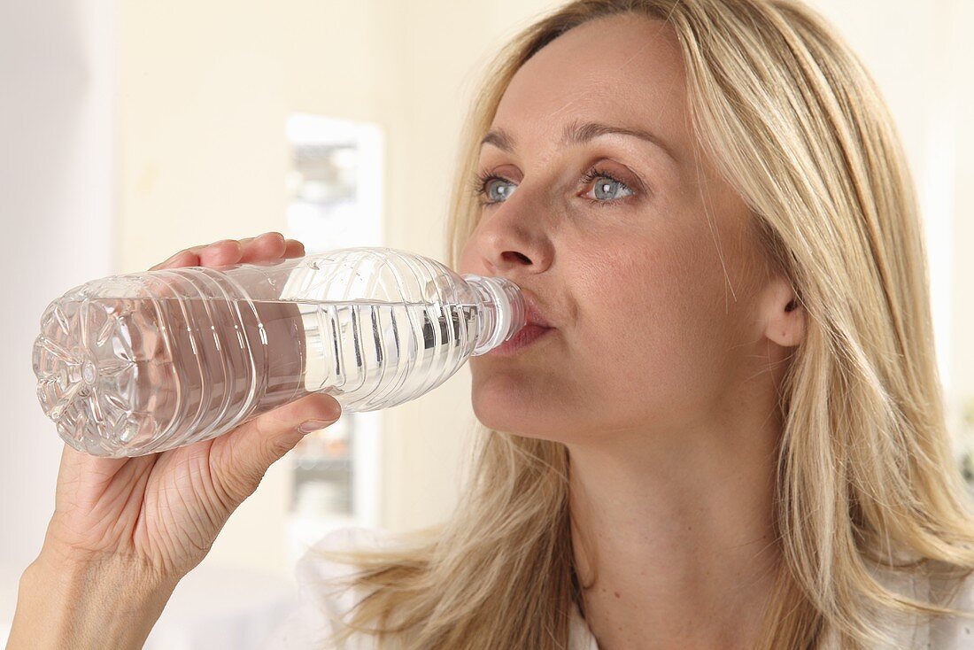 Frau trinkt Wasser aus Plastikflasche