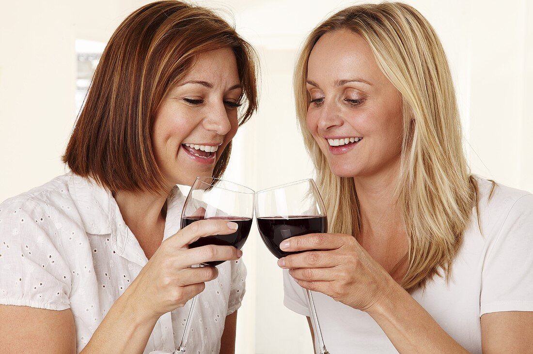 Zwei Frauen stossen mit Rotweingläsern an