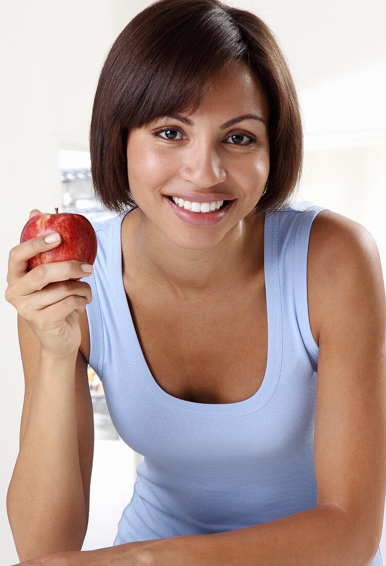 Young woman holding apple, close-up, portrait